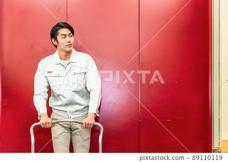 A man pushing a dolly in front of a freight elevator A man pushing a dolly in front of a freight elevator 89110119