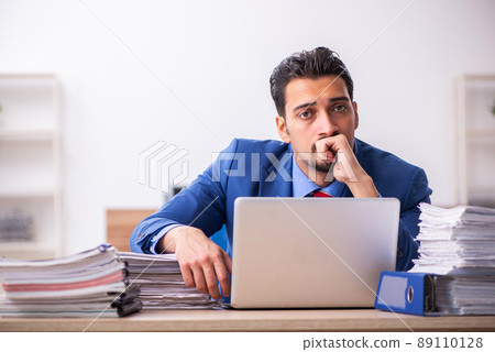 Young male employee unhappy with excessive work at workplace 89110128