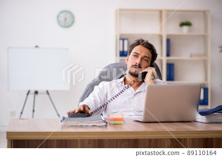 Young male employee sitting in the office Young male employee sitting in the office 89110164
