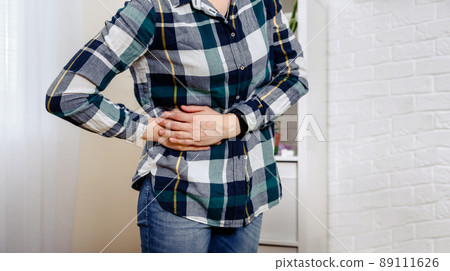 Young female touching her right side in pain . Woman has waist pain. 89111626