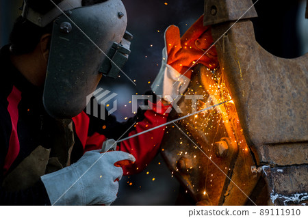 Welder in iron mask helmet welds with electric arc steel welding, Industrial worker at the factory welding steel structure, Welder is welding metalwork manufacturing and construction maintenance 89111910