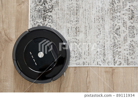 Robotic vacuum cleaner on the floor in cozy modern living room 89111934