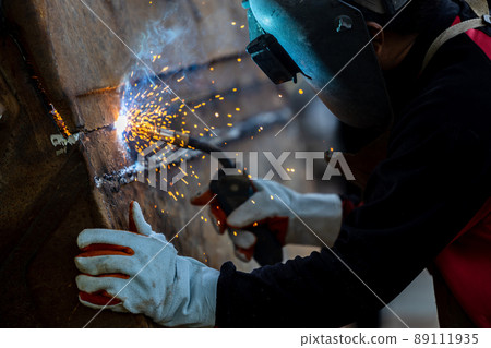 Welder in iron mask helmet welds with electric arc steel welding, Industrial worker at the factory welding steel structure, Welder is welding metalwork manufacturing and construction maintenance Welder in iron mask helmet welds with electric arc steel welding, Industrial worker at the factory welding steel structure, Welder is welding metalwork manufacturing and construction maintenance 89111935