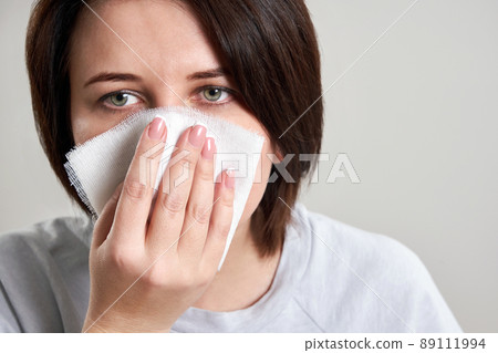 Young woman holding gauze or bandage instead of medical face mask to protect from coronavirus. shortage of mask concept Young woman holding gauze or bandage instead of medical face mask to protect from coronavirus. shortage of mask concept 89111994