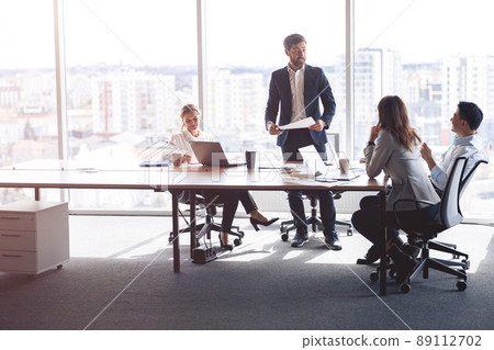 people standing near table, team of young businessmen working and communicating together in office 89112702