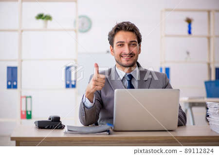 Young male employee sitting at workplace Young male employee sitting at workplace 89112824