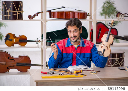 Young man repairing musical instruments at workshop Young man repairing musical instruments at workshop 89112996