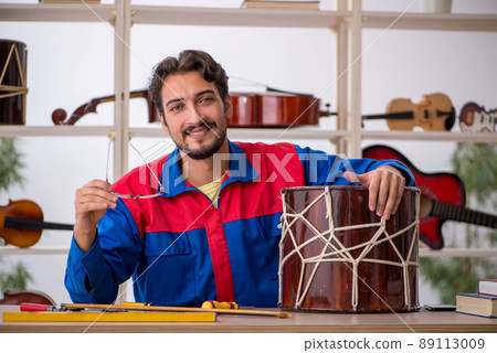 Young man repairing musical instruments at workshop 89113009