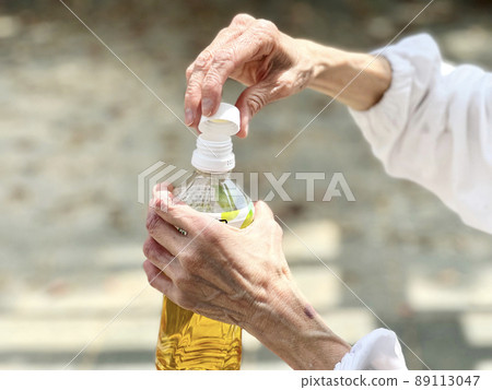 Hands of an elderly woman who closes the lid of a plastic bottle Hands of an elderly woman who closes the lid of a plastic bottle 89113047