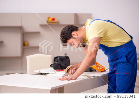 Young male carpenter repairing table at home Young male carpenter repairing table at home 89113341