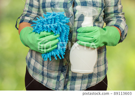Woman with a bottle of washing liquid and a rag. 89113603