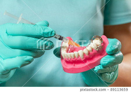 Dentist with layout of the human jaw and syringe. 89113659