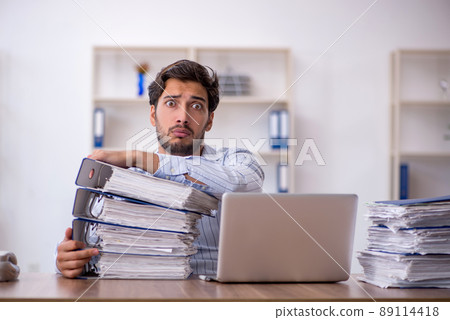 Young male employee unhappy with excessive work in the office 89114418