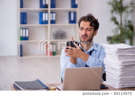 Young male employee and too much work in the office Young male employee and too much work in the office 89114974
