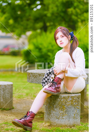 A beautiful older sister taking a break in a beautiful park with fresh green in the cheerful early summer A beautiful older sister taking a break in a beautiful park with fresh green in the cheerful early summer 89115101