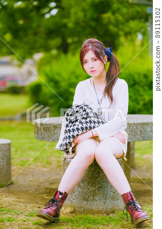 A beautiful older sister taking a break in a beautiful park with fresh green in the cheerful early summer A beautiful older sister taking a break in a beautiful park with fresh green in the cheerful early summer 89115102