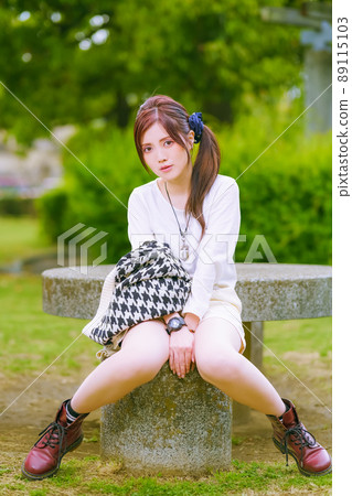 A beautiful older sister taking a break in a beautiful park with fresh green in the cheerful early summer A beautiful older sister taking a break in a beautiful park with fresh green in the cheerful early summer 89115103