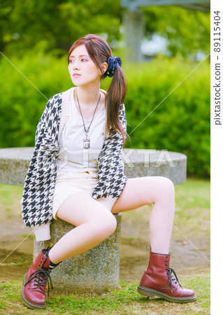 A beautiful older sister taking a break in a sunny park in the early summer with beautiful fresh greenery A beautiful older sister taking a break in a sunny park in the early summer with beautiful fresh greenery 89115404