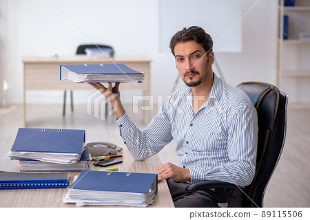 Young male employee and too much work in the office Young male employee and too much work in the office 89115506