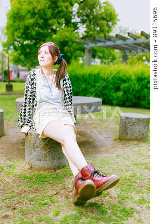 一個美麗的姐姐在初夏時在一個美麗的公園裡休息，綠意盎然 89115696