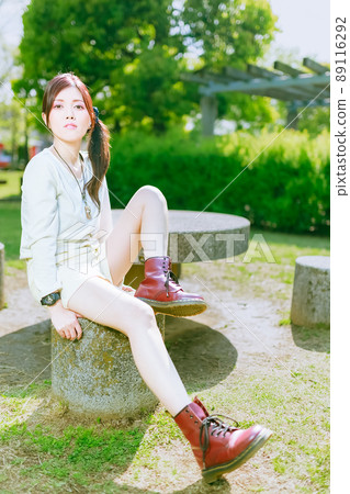 A beautiful older sister who enjoys a walk in a beautiful park with fresh green in the cheerful early summer 89116292