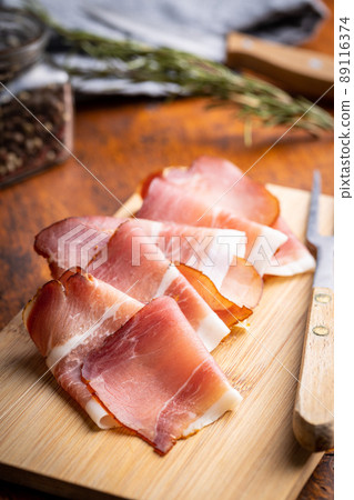 Sliced schwarzwald ham. Dried prosciutto ham on cutting board. 89116374