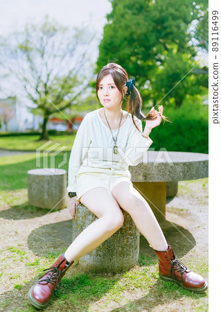 A beautiful older sister taking a walk in a beautiful park with fresh greenery in the cheerful early summer A beautiful older sister taking a walk in a beautiful park with fresh greenery in the cheerful early summer 89116499