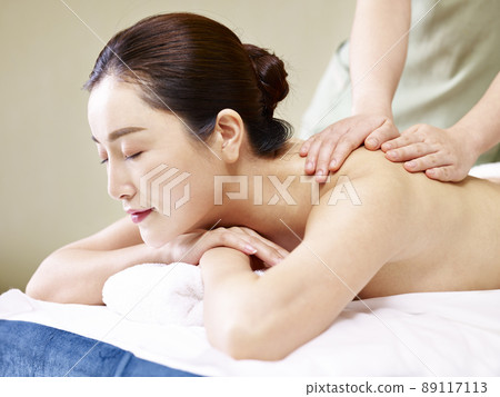 side view of a beautiful young asian woman receiving massage in spa salon, eyes closed 89117113