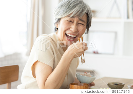 A smiling woman in her 50s having breakfast A smiling woman in her 50s having breakfast 89117145