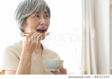 一個 50 多歲的微笑女人吃早餐 一個 50 多歲的微笑女人吃早餐 89117147
