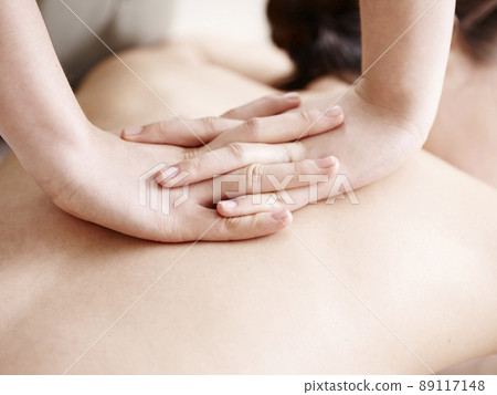 close-up of hands of a masseuse massaging back of a young asian woman 89117148