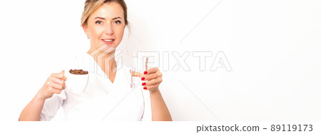 Coffee with water. The female nutritionist holds a cup of coffee beans and a glass of water in her hands on white background 89119173