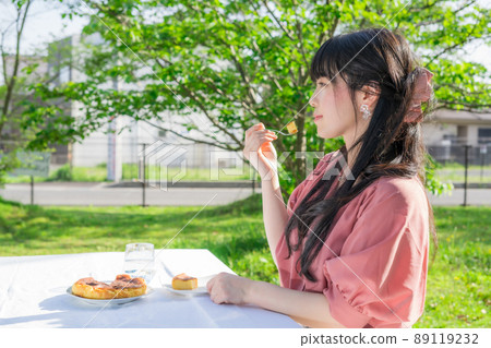Woman eating homemade cheesecake outdoors 89119232