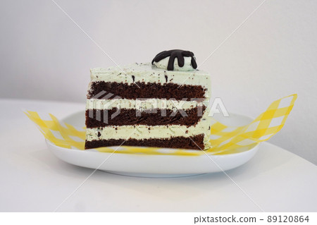 side view chocolate cake, placed on a yellow and white plastic plate on a white ceramic dish side view chocolate cake, placed on a yellow and white plastic plate on a white ceramic dish 89120864