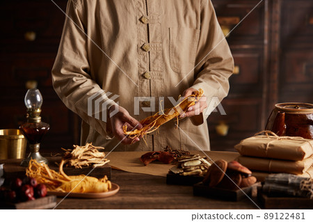 A moment of apocathery measuring ginseng in gold scale with chinese traditional medicine in wooden table 89122481