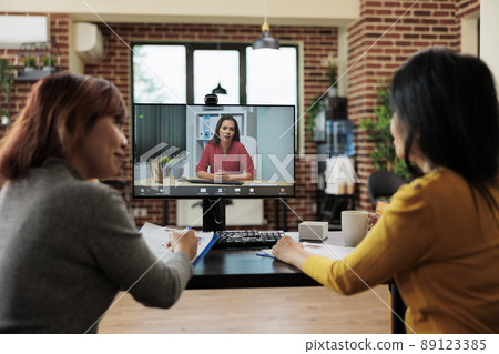 Team of businesswomen working at job recruitment discussing curriculum vitae with remote applicant during online videocall meeting conference in startup company office. Teleconference call on screen 89123385