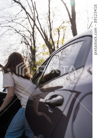 Young woman gets into a modern car 89123418