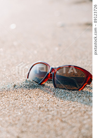 Sunglasses on the sand. Summer vacation concept. Protective sunglasses on sandy beach at tropical seaside on warm sunny day. Sunglasses on the sand. Summer vacation concept. Protective sunglasses on sandy beach at tropical seaside on warm sunny day. 89123726