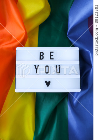 Rainbow flag with lightbox and text BE YOU. Rainbow lgbtq flag made from silk material. Symbol of LGBTQ pride month. Equal rights. Peace and freedom Rainbow flag with lightbox and text BE YOU. Rainbow lgbtq flag made from silk material. Symbol of LGBTQ pride month. Equal rights. Peace and freedom 89123883
