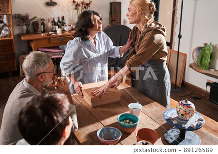 Elderly woman touching her female teacher with hand and thanking to her Elderly woman touching her female teacher with hand and thanking to her 89126589