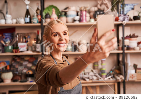 Overjoyed woman smiling while taking selfie at her smartphone Overjoyed woman smiling while taking selfie at her smartphone 89126682