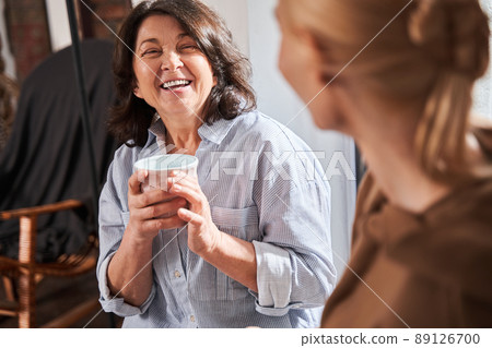 Woman laughing with her young teacher and listening her while drinking coffee Woman laughing with her young teacher and listening her while drinking coffee 89126700