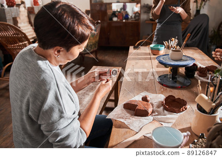 Woman sitting at the table and preparing making something from clay with special stick Woman sitting at the table and preparing making something from clay with special stick 89126847