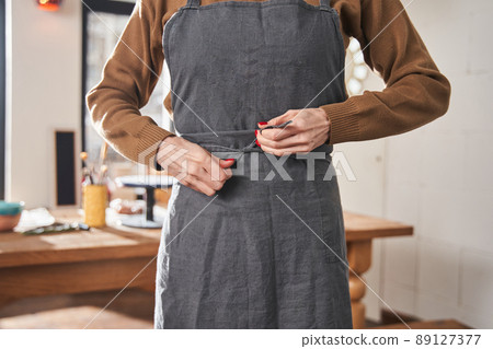 Woman wiping her apron while preparing to the work at her pottery art studio Woman wiping her apron while preparing to the work at her pottery art studio 89127377