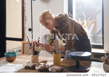 Designer or artist preparing to making sculpt from clay at her studio while working Designer or artist preparing to making sculpt from clay at her studio while working 89127423