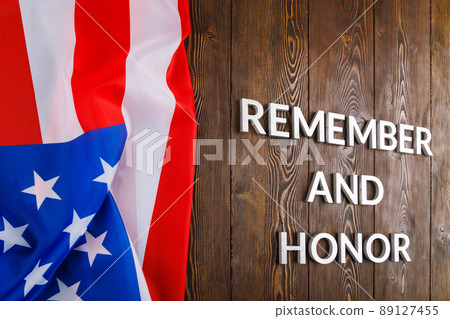words remember and honor laid with silver metal letters on wooden background with USA flag on the left side 89127455
