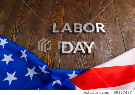 words labor day laid with silver metal letters on wooden surface with crumpled USA flag on bottom side words labor day laid with silver metal letters on wooden surface with crumpled USA flag on bottom side 89127457