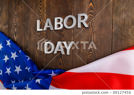 words labor day laid with silver metal letters on wooden surface with crumpled USA flag on bottom side words labor day laid with silver metal letters on wooden surface with crumpled USA flag on bottom side 89127458