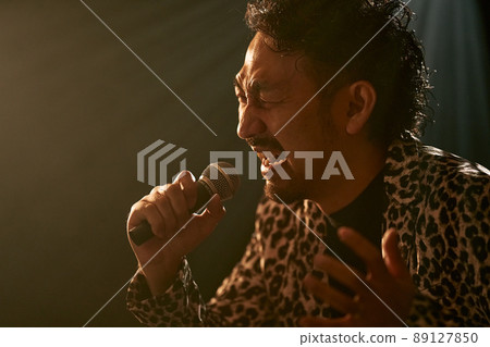 Bearded man in a leopard print jacket singing enthusiastically Bearded man in a leopard print jacket singing enthusiastically 89127850