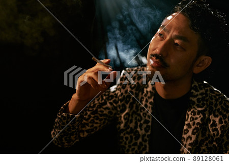 Bearded man in a leopard print jacket smoking a cigarette Bearded man in a leopard print jacket smoking a cigarette 89128061